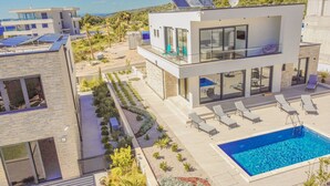 Ein modernes, zweistöckiges Haus mit Dachgarten, Pool und Meerblick.