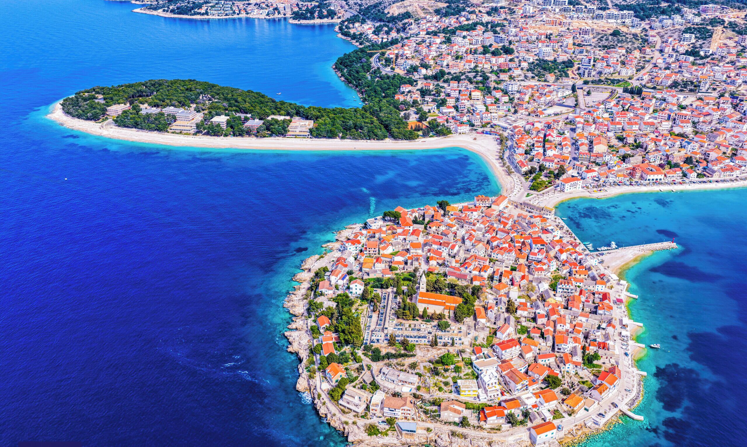 Une vue aérienne d’une ville côtière avec une île centrale où les bâtiments sont très rapprochés les uns des autres et dont la côte est incurvée.