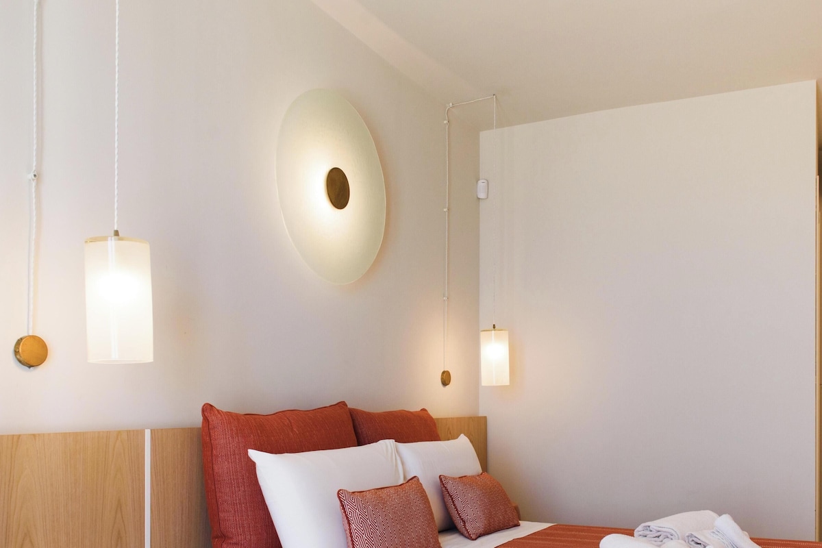 Een hotelkamer met een bed, een wandlamp en een deur.