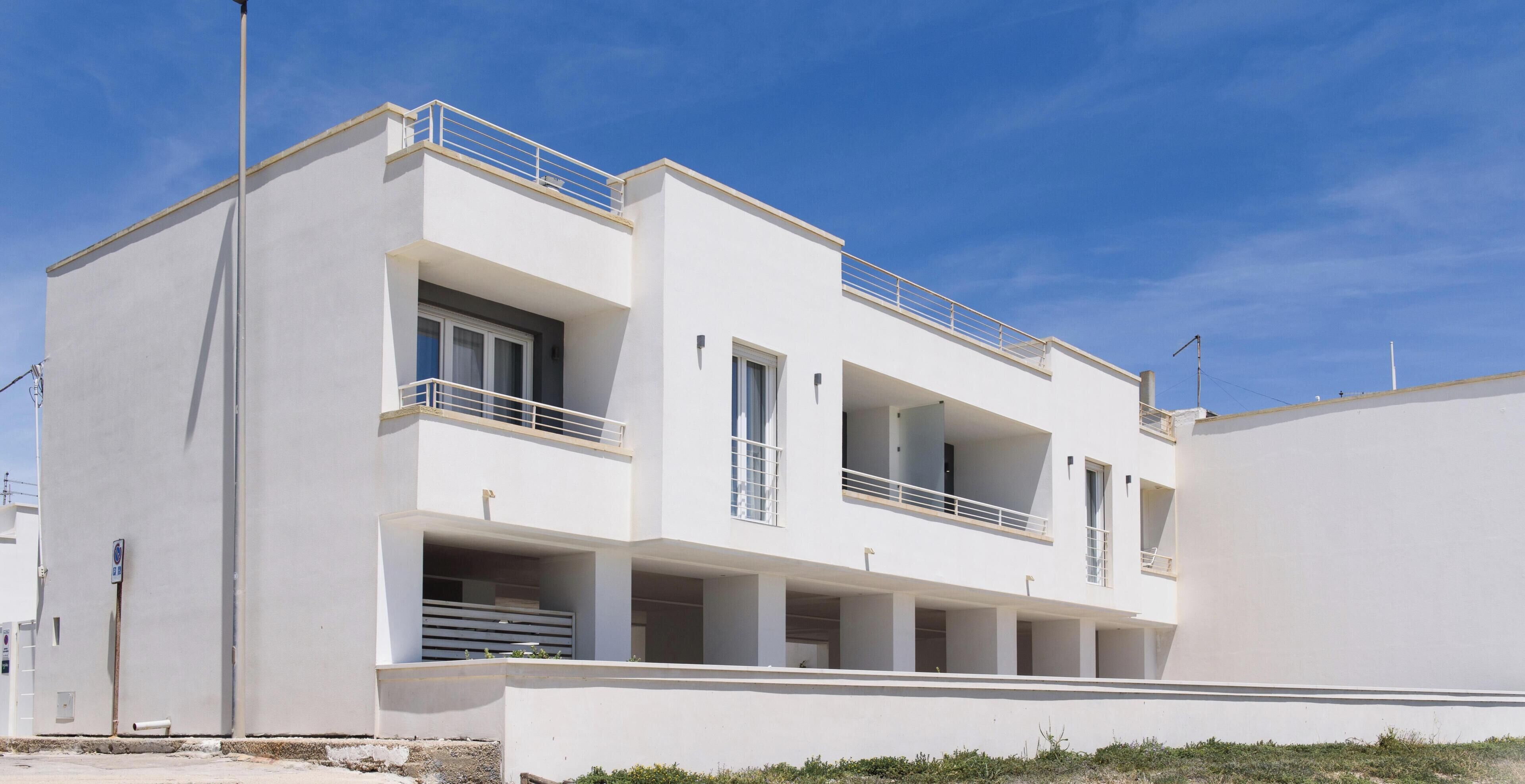 Un edificio moderno de dos pisos con balcones, ventanas amplias y techo plano.