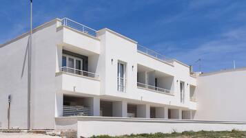 A modern two-story building with balconies, large windows, and a flat roof.