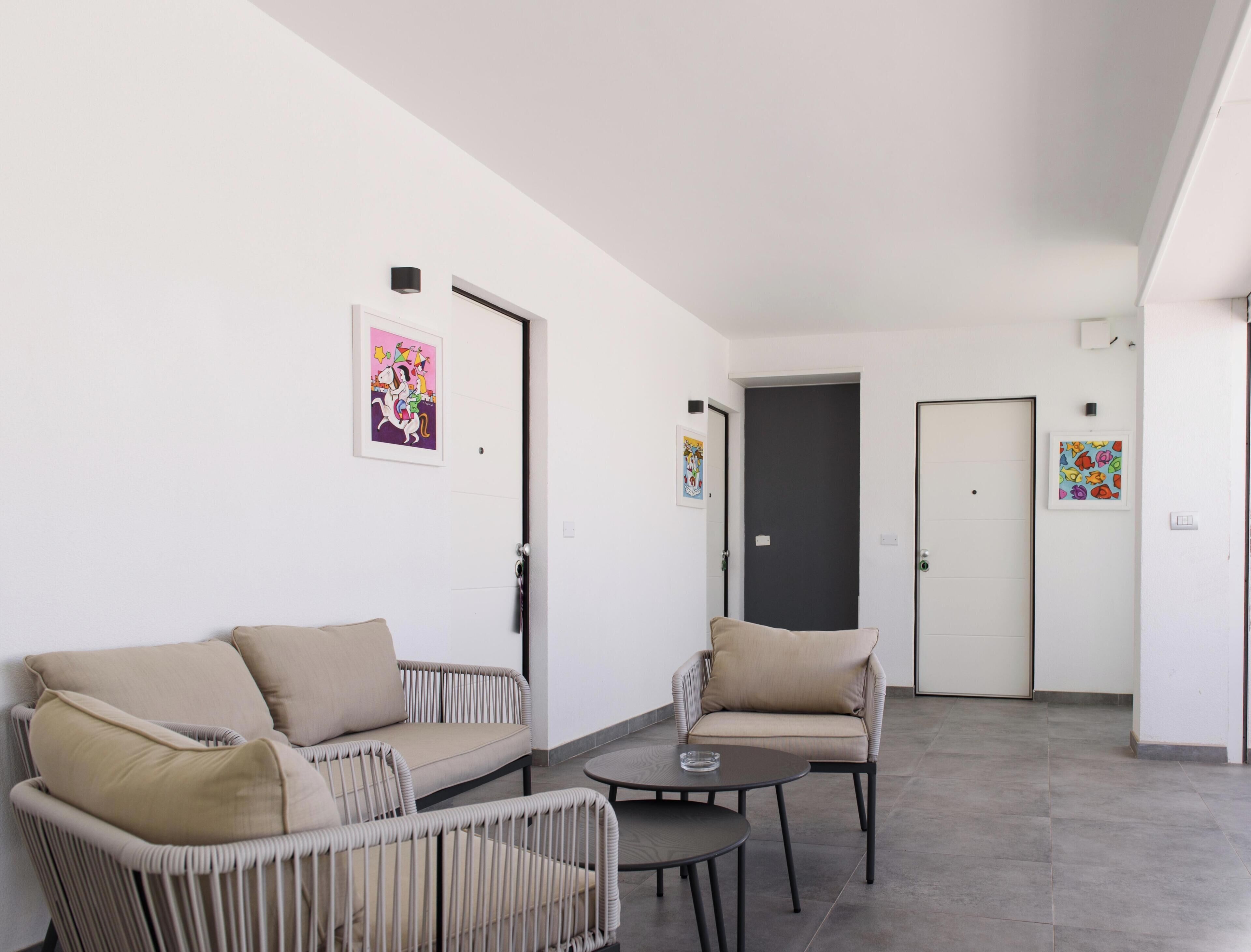 Une pièce comprenant un canapé, un fauteuil et une petite table, avec des portes et des œuvres d’art sur les murs.