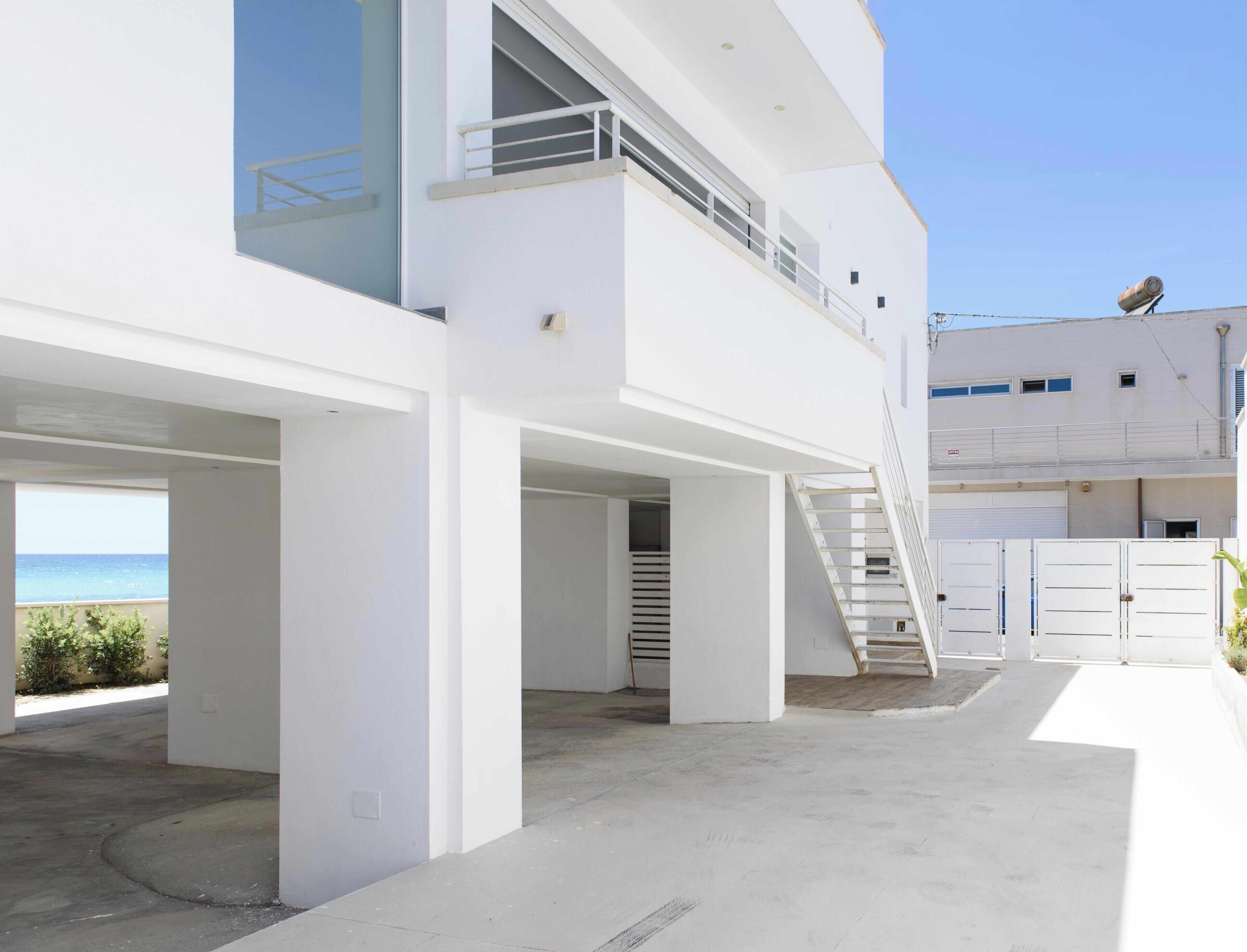 En modern bostadsbyggnad med flera våningar, en balkong, en trappa och utsikt över havet.