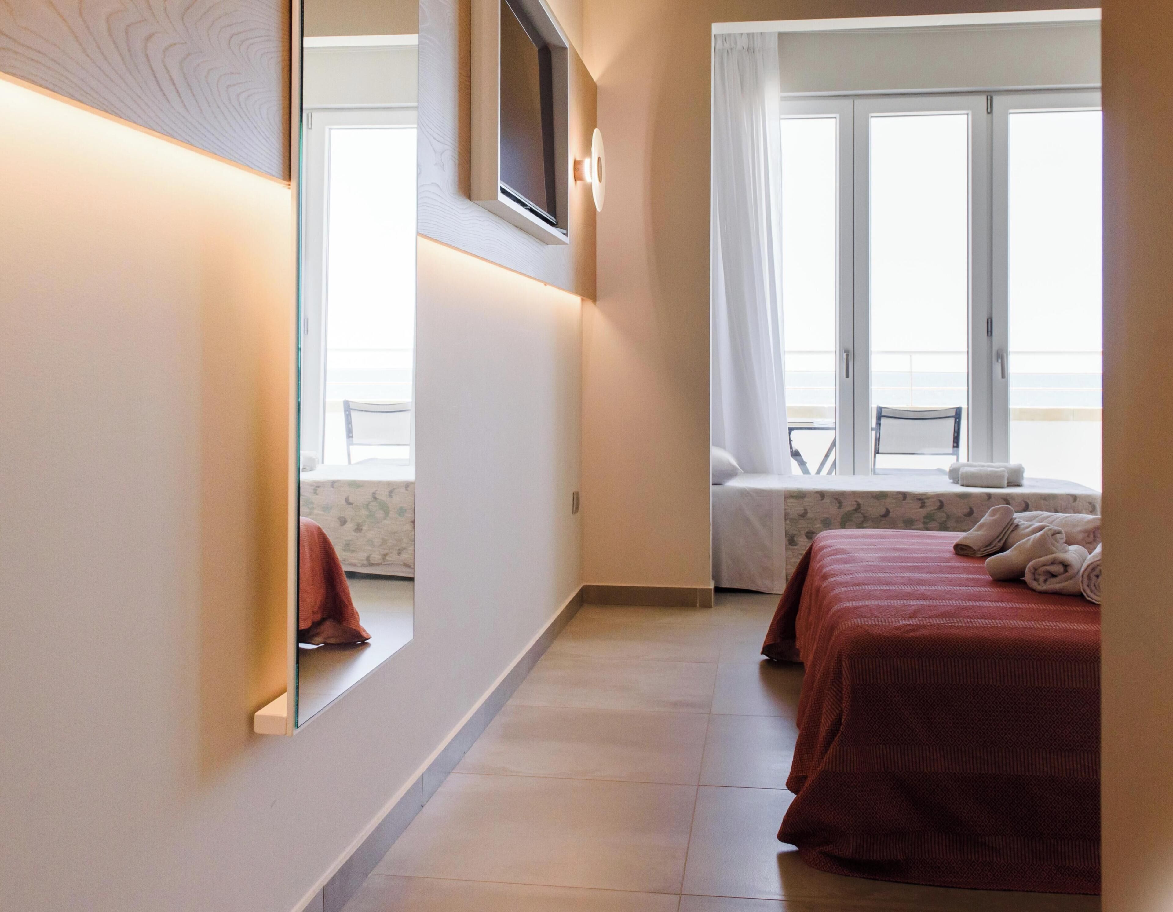 Una habitación de hotel con una cama, una ventana, una silla y una mesa.