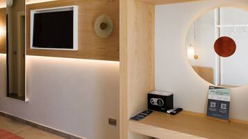 Una hall d'albergo moderna con una TV a schermo piatto, uno specchio rotondo, una reception in legno e un cartello per Holiday Apartment Collection.