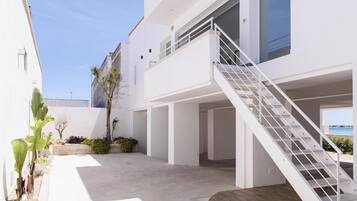 Un bâtiment moderne à l’extérieur blanc, avec un escalier menant à un balcon et une vue sur la mer.