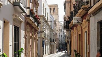 Une rue étroite bordée de bâtiments historiques, avec des balcons ornés de plantes en pot et un ciel dégagé au-dessus.