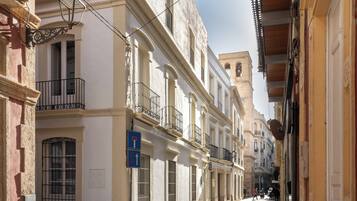 A narrow street lined with historic buildings, featuring balconies and a clear sky.