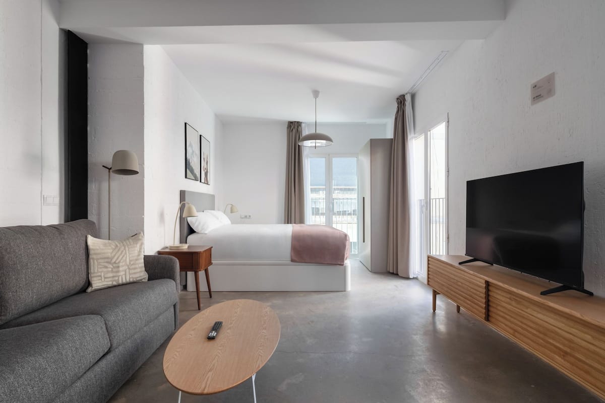 Ein modernes Hotelzimmer mit einem großen Bett, einer Couch, einem Fernseher und einem kleinen Tisch.