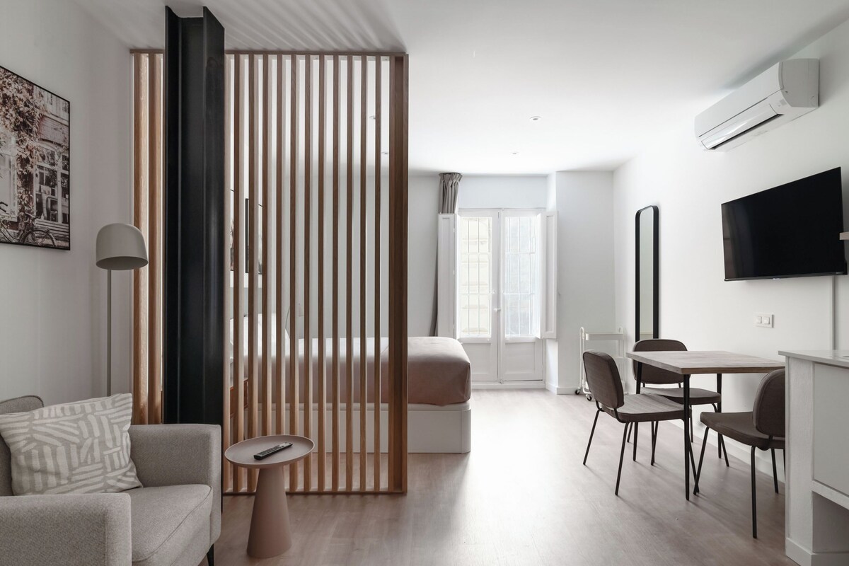 A modern living room with a sofa, a coffee table, a TV, and a dining area with chairs and a table.