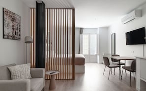 Ein modernes Wohnzimmer mit einer Couch, einem Couchtisch, einem Fernseher und einem Essbereich mit Stühlen und einem Tisch.