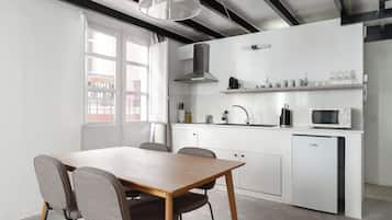 Una cocina moderna con armarios blancos, microondas integrado y un refrigerador compacto.