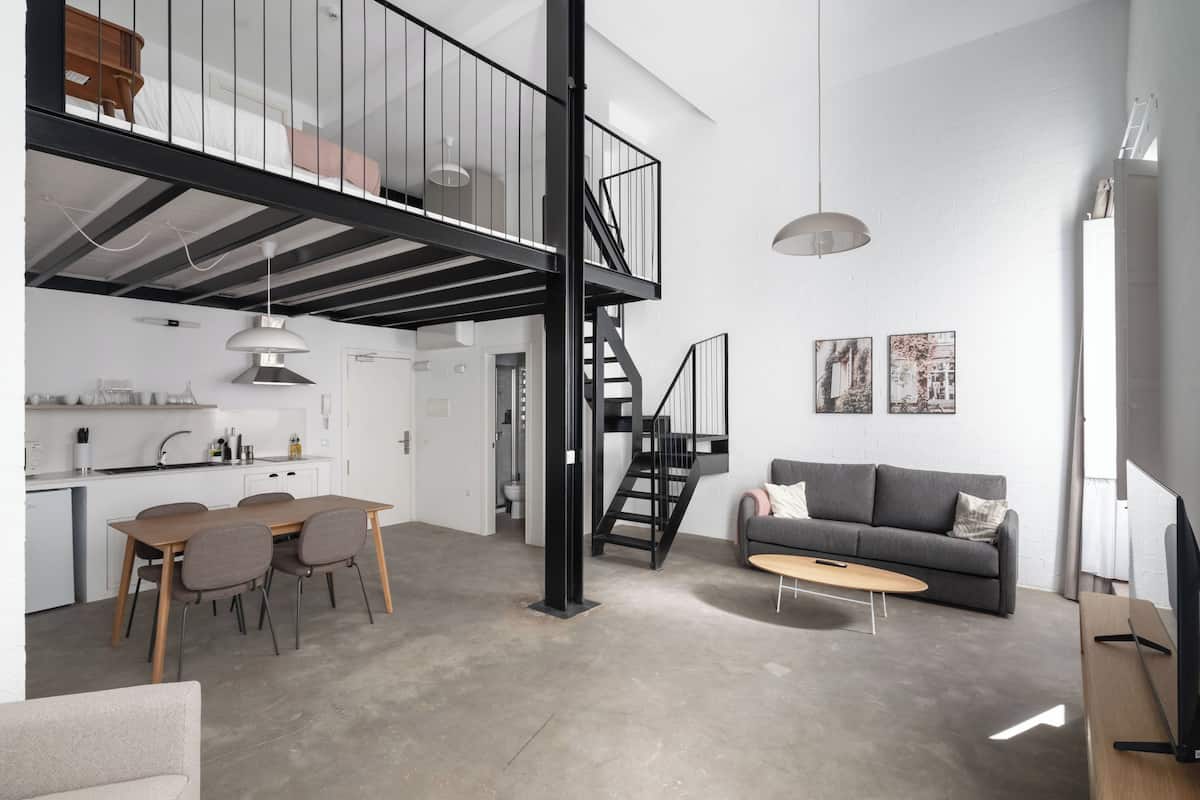 Ein geräumiger Wohnbereich mit Esstisch, Sofa und einer Treppe zu einer oberen Ebene.