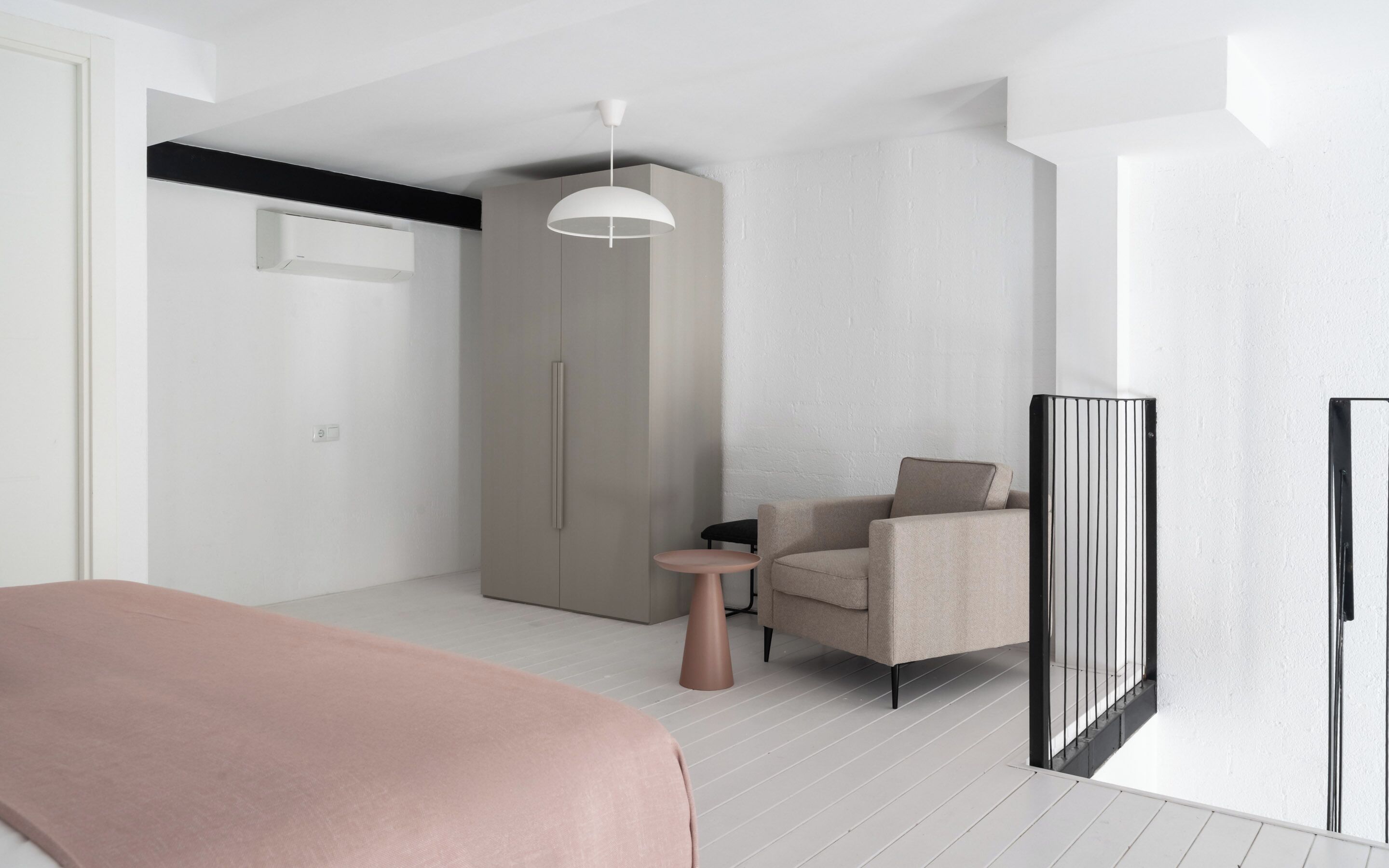A modern bedroom with a bed, a chair, a small table, and a wardrobe.