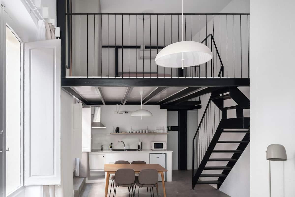 Eine moderne Küche mit Essbereich, einer Treppe und einer Couch.