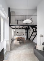 Una cocina moderna con comedor, una escalera y un sofá.