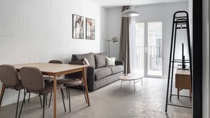 A modern living room with a wooden dining table, grey sofa, and a black metal ladder. - Limehome Almeria C. Hernán Cortés (Almeria)