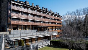 Ένα πολυώροφο κτίριο με μπαλκόνια, μια σκάλα και έναν μικρό κήπο.
