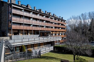 Un edificio de varios pisos con balcones, una escalera y un pequeño jardín.