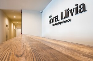 Un pasillo de hotel con piso de madera y un letrero en la pared que dice "HOTEL LÍVIA Cycling Experience".