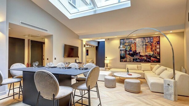 Un soggiorno moderno con zona pranzo, divano e un quadro raffigurante una veduta cittadina.