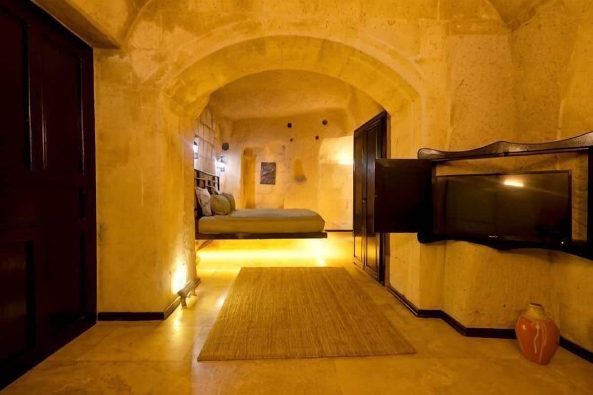 A narrow hallway with a bed, a flat-screen TV, and a vase.