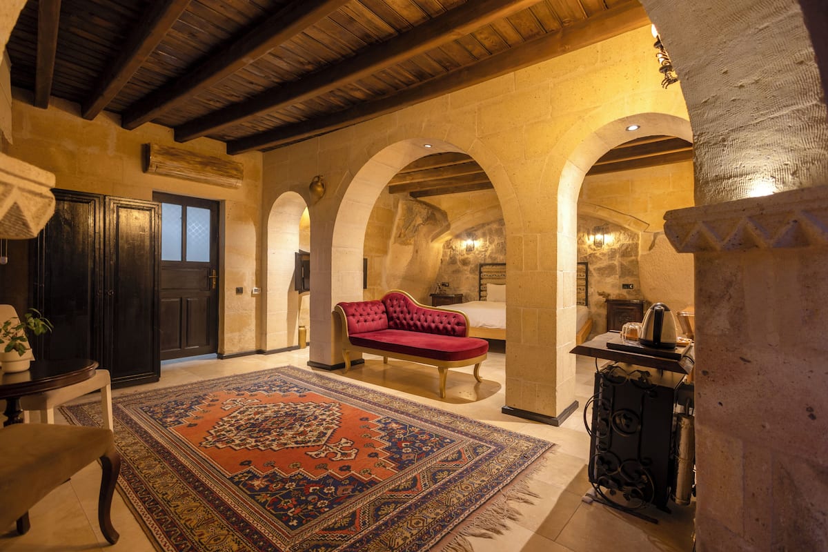 A traditional room with a red sofa, a patterned rug, and stone arches.