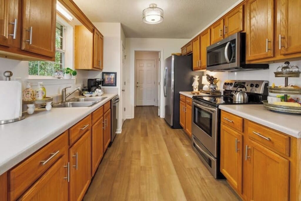 A kitchen with wooden cabinets, stainless steel appliances, and a white countertop.