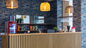 A reception area with a wooden counter, a Coca-Cola refrigerator, and hanging lights. - Hotel A4 Wrocław (Kobierzyce)