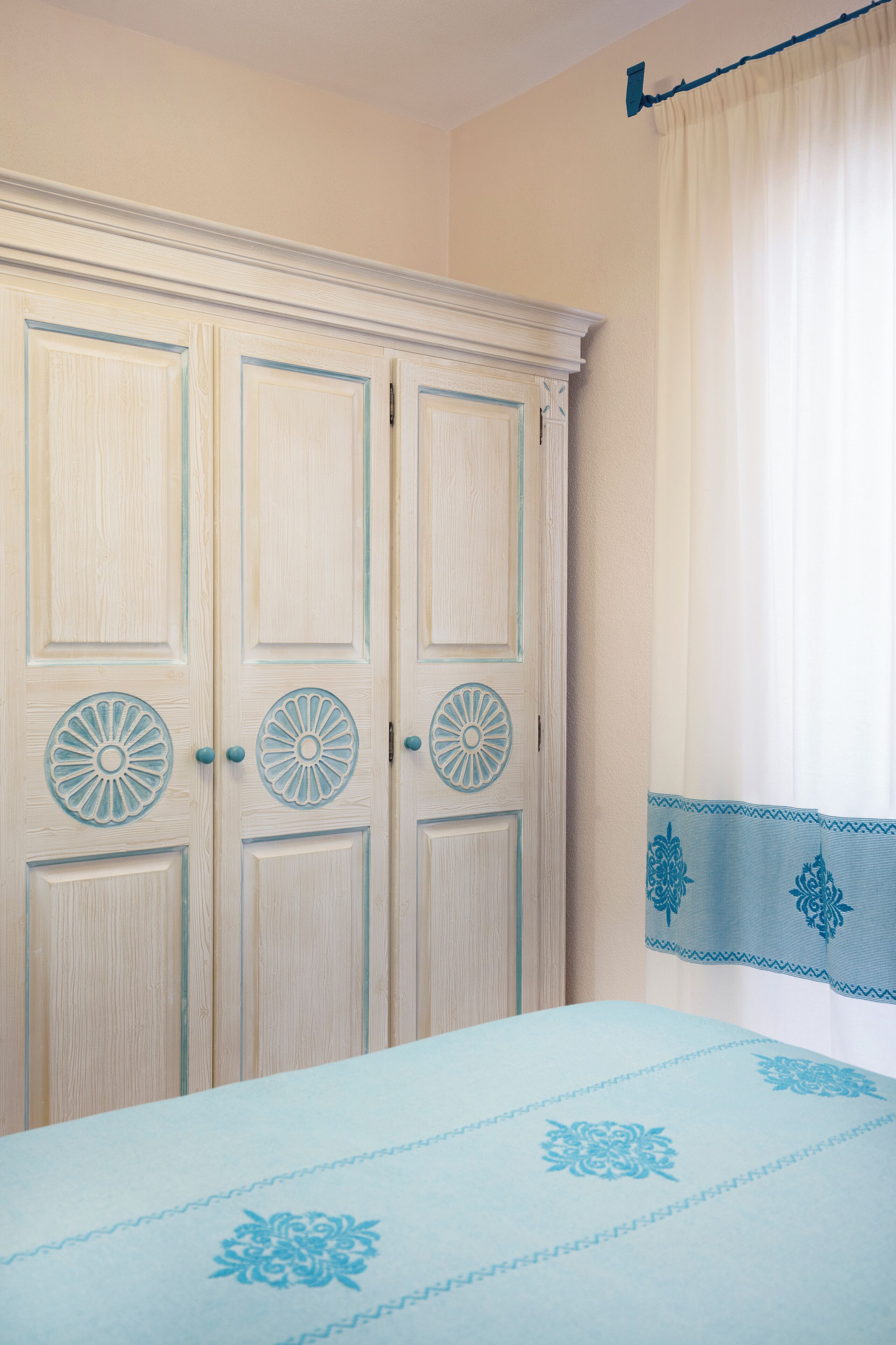 Un dormitorio con cama, armario y ventana con cortinas.