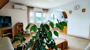 A modern living room with a television, wooden furniture, and a large plant. - Charming 2-bedroom, family friendly cottage in Miskolc at the Bükk Mountains (Miskolc)