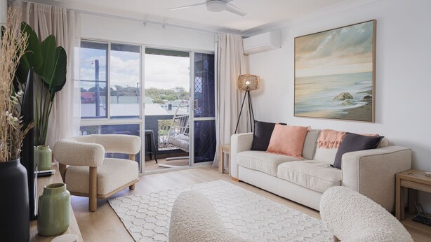 A modern living room with a white sofa, two armchairs, a floor lamp, and a large window with a view of the sea. - Hidden Gem - 150m from Urunga Sea Lido (Urunga)