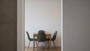 A dining area with a wooden table and four green upholstered chairs. - Hidden Gem - 150m from Urunga Sea Lido (Urunga)