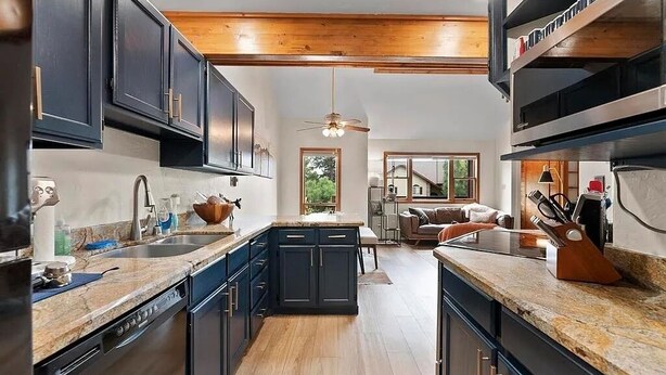A modern kitchen with dark cabinetry, granite countertops, and a central island.