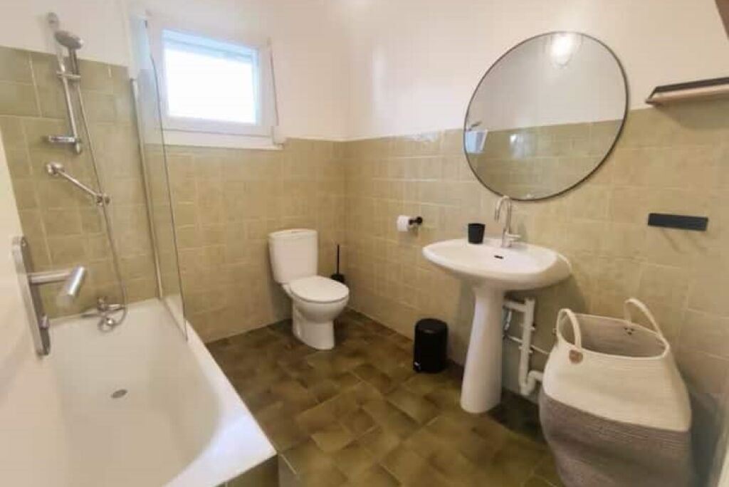 A bathroom with a bathtub, toilet, sink, and a mirror.