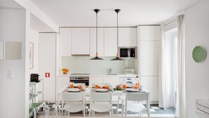 Una cocina moderna con armarios blancos, un microondas y un comedor con una mesa dispuesta para cuatro.