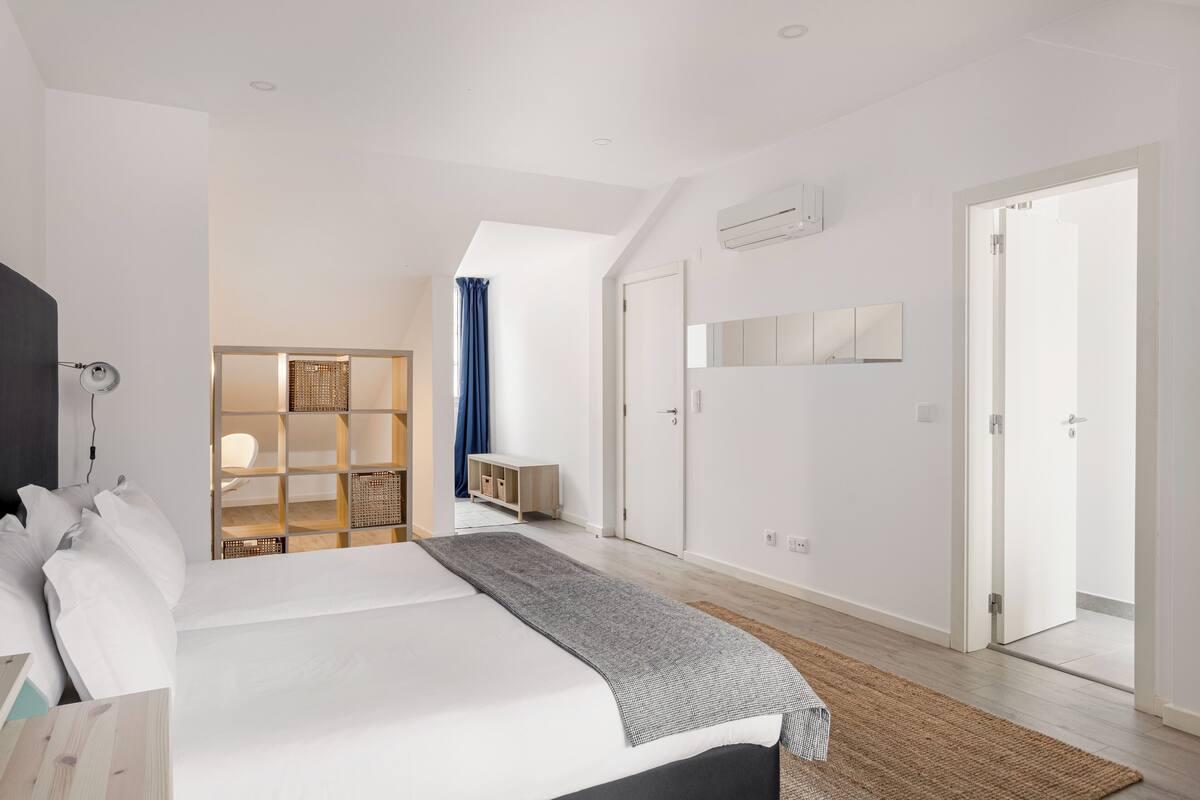 A modern bedroom with a large bed, a wooden wardrobe, a mirror, and a ceiling fan.