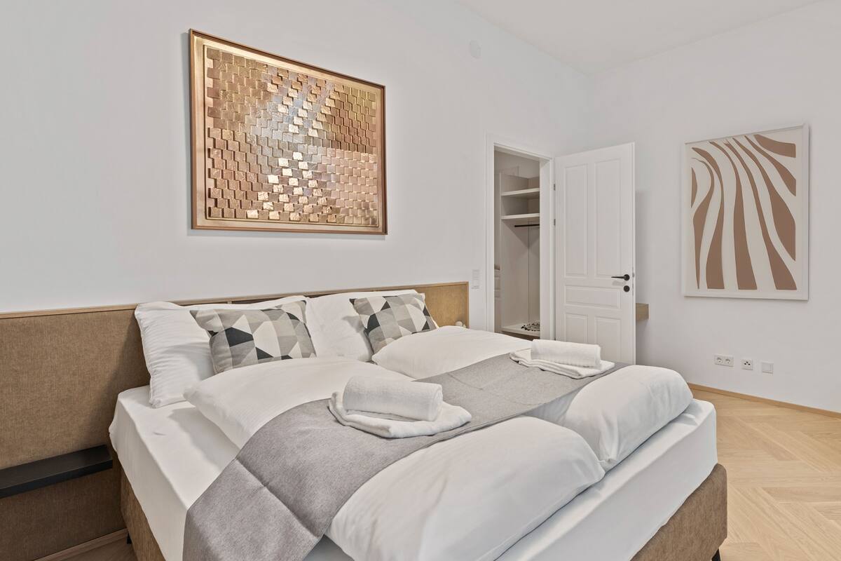 Quarto moderno com uma cama grande, um guarda-roupa e um banheiro visível por uma porta aberta.