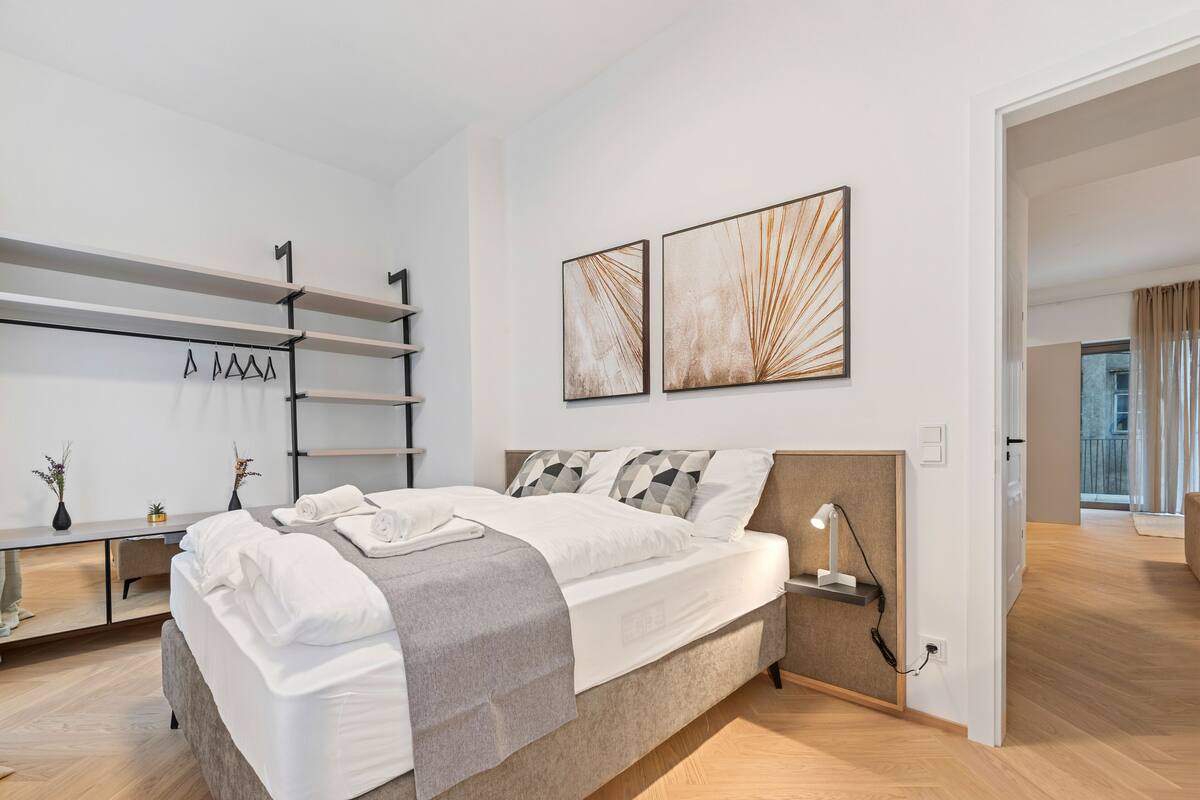 Quarto moderno com cama, mesas de cabeceira, escrivaninha e obras de arte na parede.