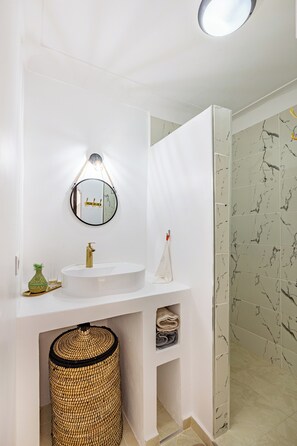 Enjoy a clean and contemporary bathroom with a round mirror, white sink, and glass shower door.