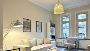 A modern living room with a sofa, a coffee table, a floor lamp, and artwork on the walls.
