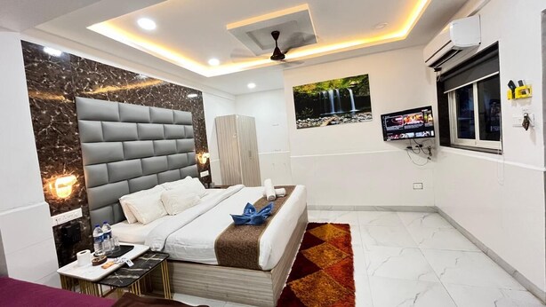 A modern hotel room with a large bed, a flat-screen TV, and a ceiling fan. - Small Daddy Plus (Calangute)