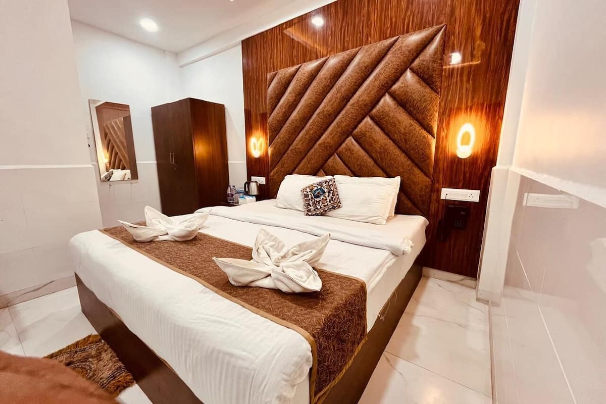A modern hotel room with a large bed, a wooden headboard, and a mirror.