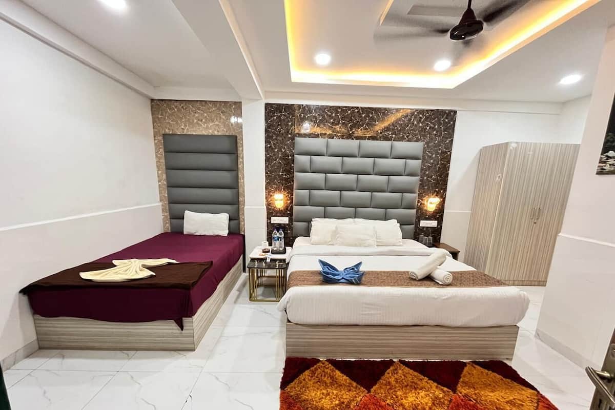 A modern hotel room with two beds, marble flooring, a marble accent wall, and a ceiling light fixture.