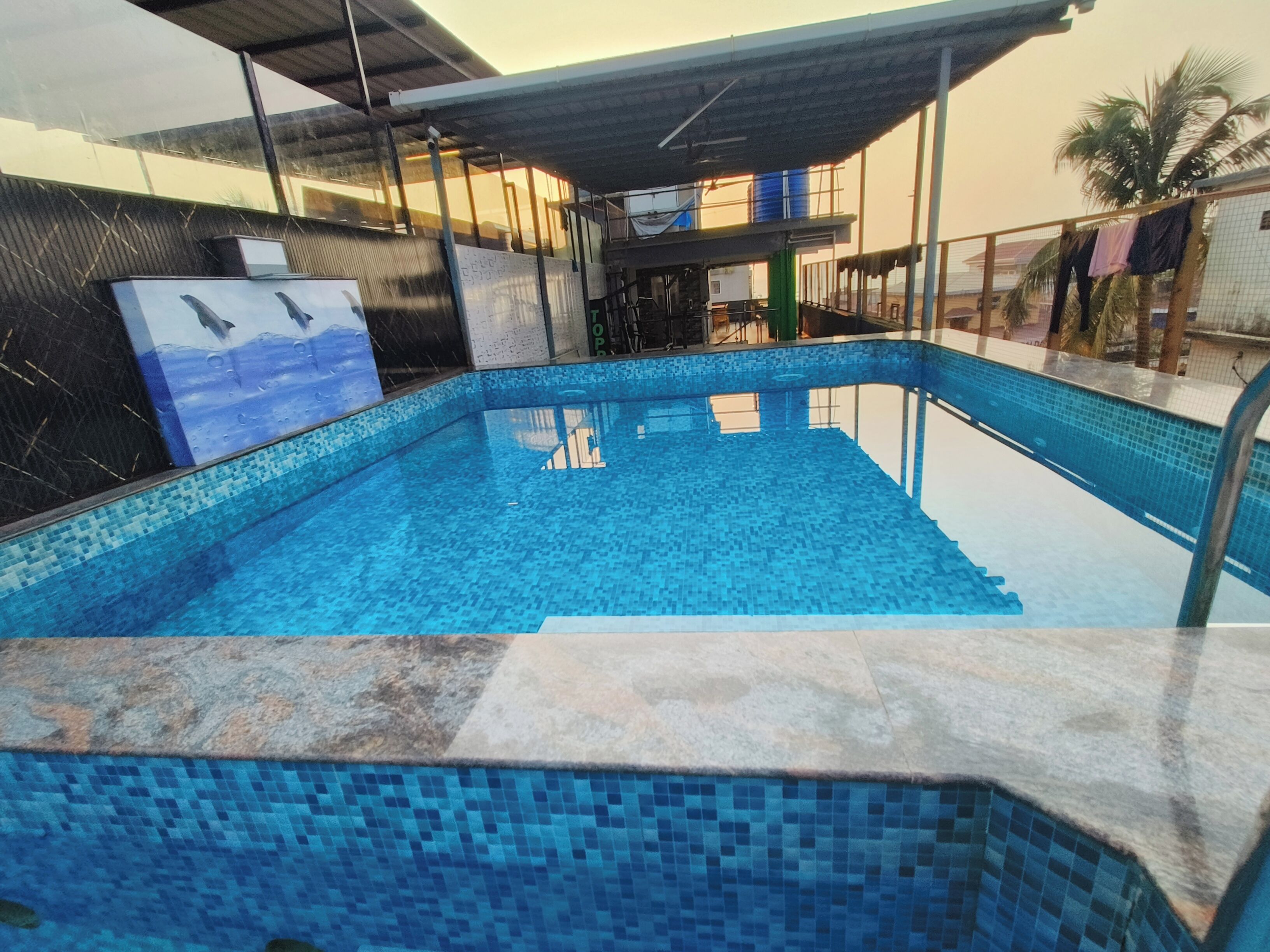 A swimming pool with a tiled edge and a covered area with a roof.