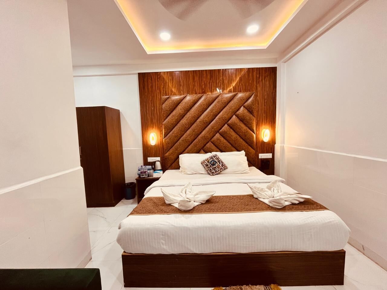 A modern hotel room with a large bed, wooden headboard, and bedside lamps.