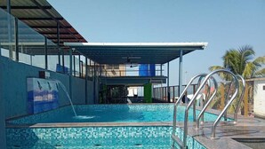A swimming pool with a tiled floor, a covered area with a roof, and metal railings. - Small Daddy Plus (Calangute)