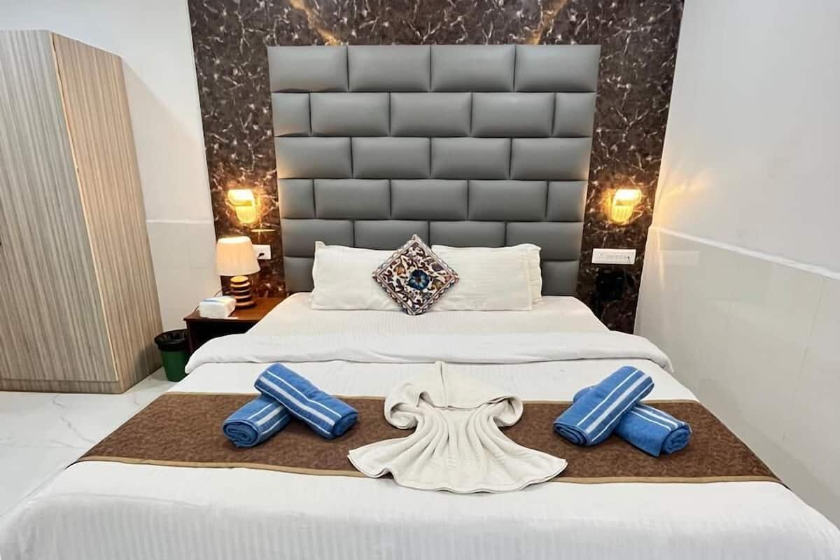 A modern hotel room with a large bed, marble wall, and ambient lighting.