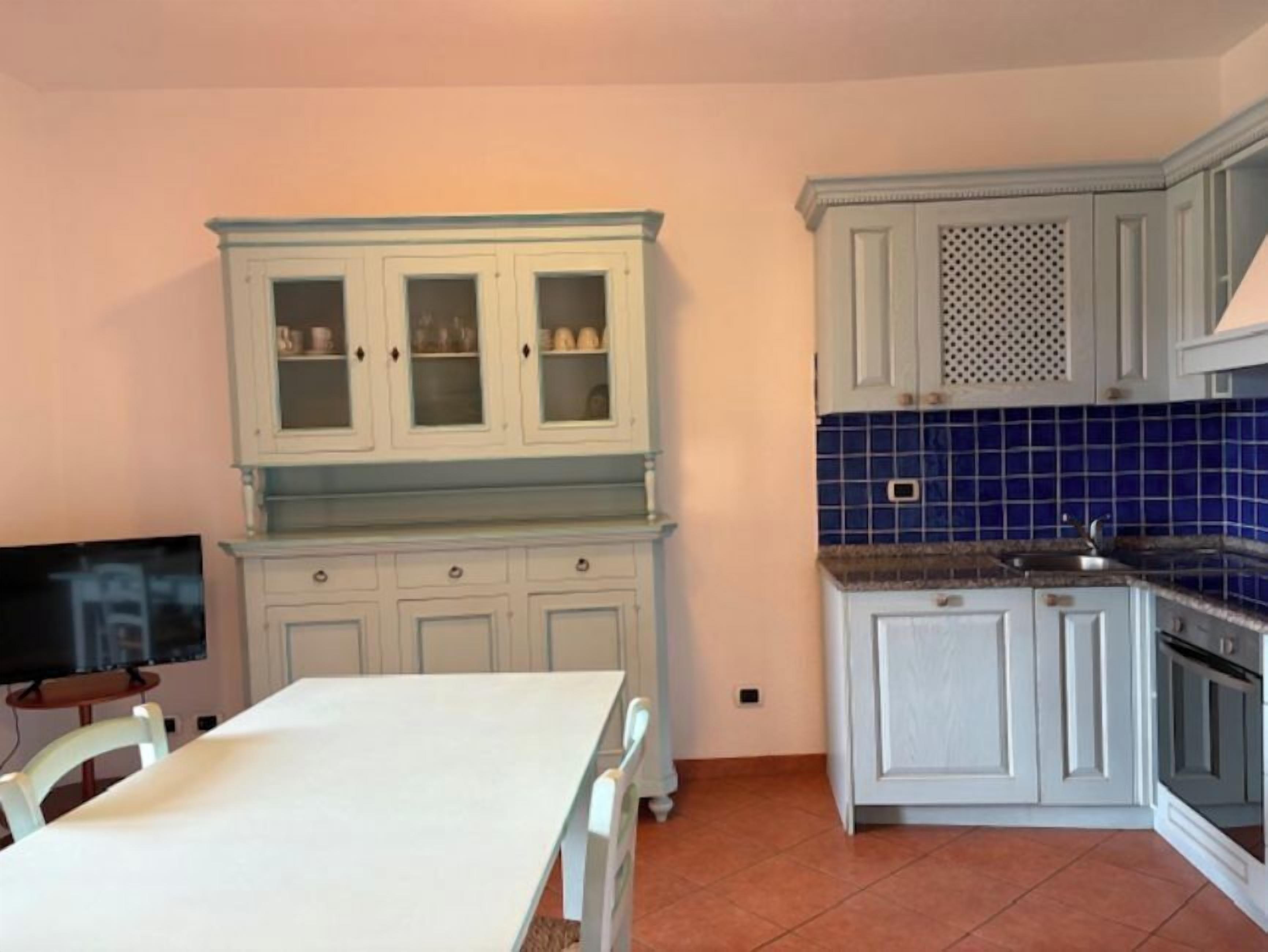 A kitchen with white cabinets, a blue tiled backsplash, and a tiled floor.