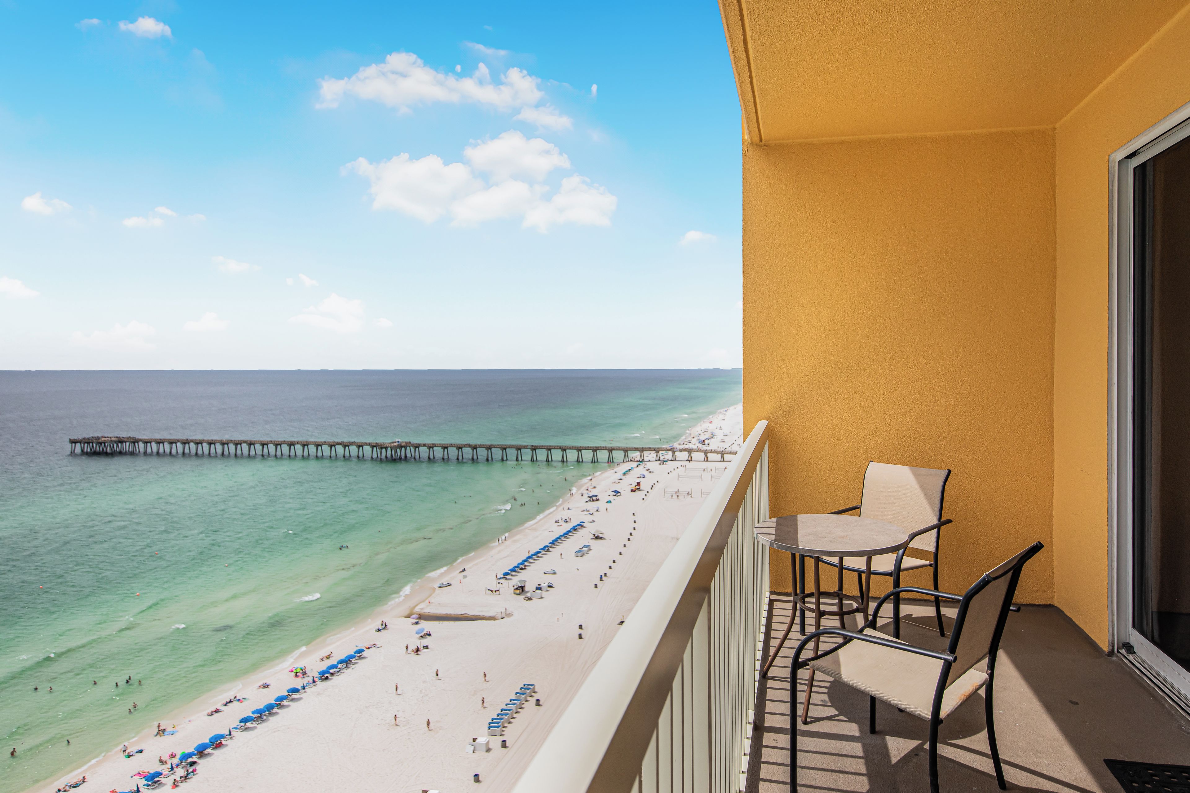 Ein Balkon mit Blick auf einen Strand und einen Steg.